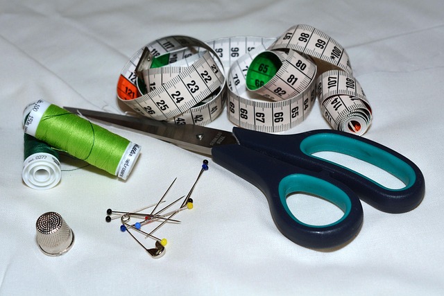 flatlay of measuring tape pins and fabric scissors textile tools